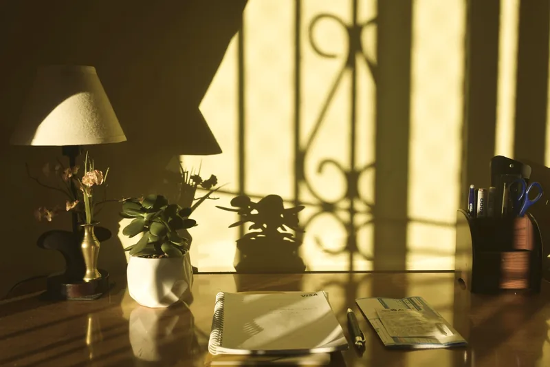 Escritorio con lámpara y plantas bañado en luz dorada de ventana